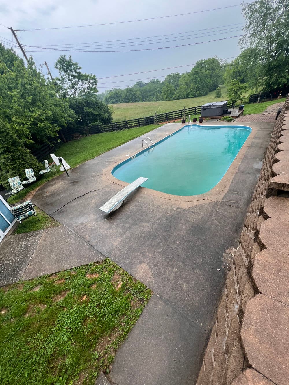 Sunny backyard with a clear pool, deck, and lush green surroundings. Ideal for relaxation.
